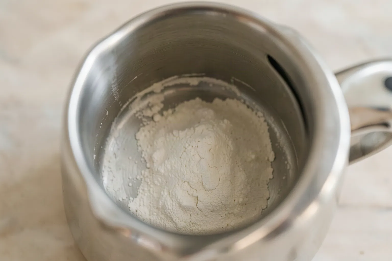 The inside of a stainless steel kettle showing a pale chalky mineral deposit